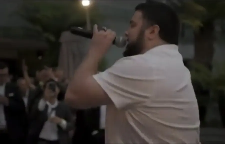 MC Solar Wind in a white tee rapping into the mic at the A Giant in the Making premiere